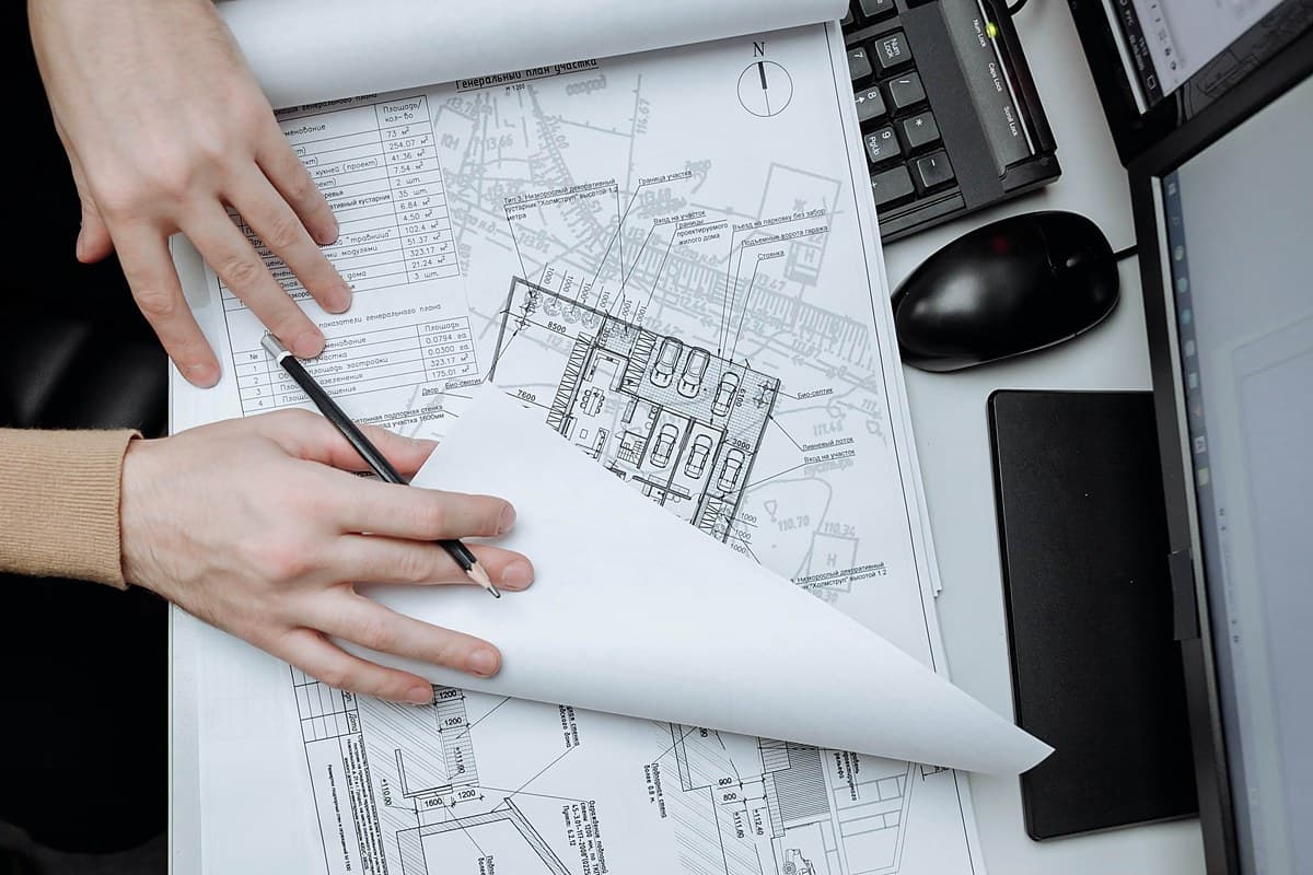 Engineer's hands marking up a site plan drawing at a desk